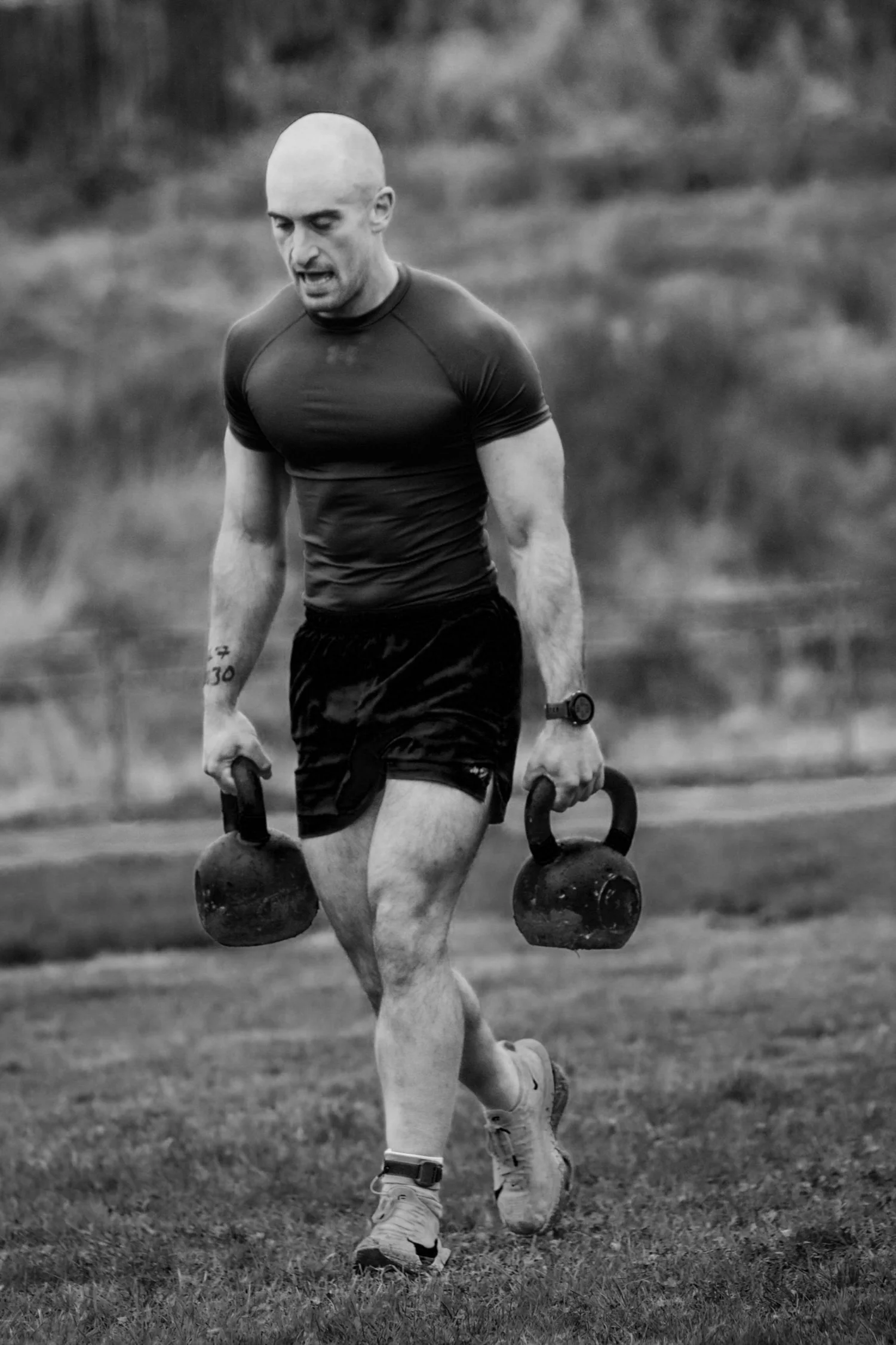 Atleet die twee kettlebells over de baan van 30 meter draagt tijdens de Farmers Carry Labour